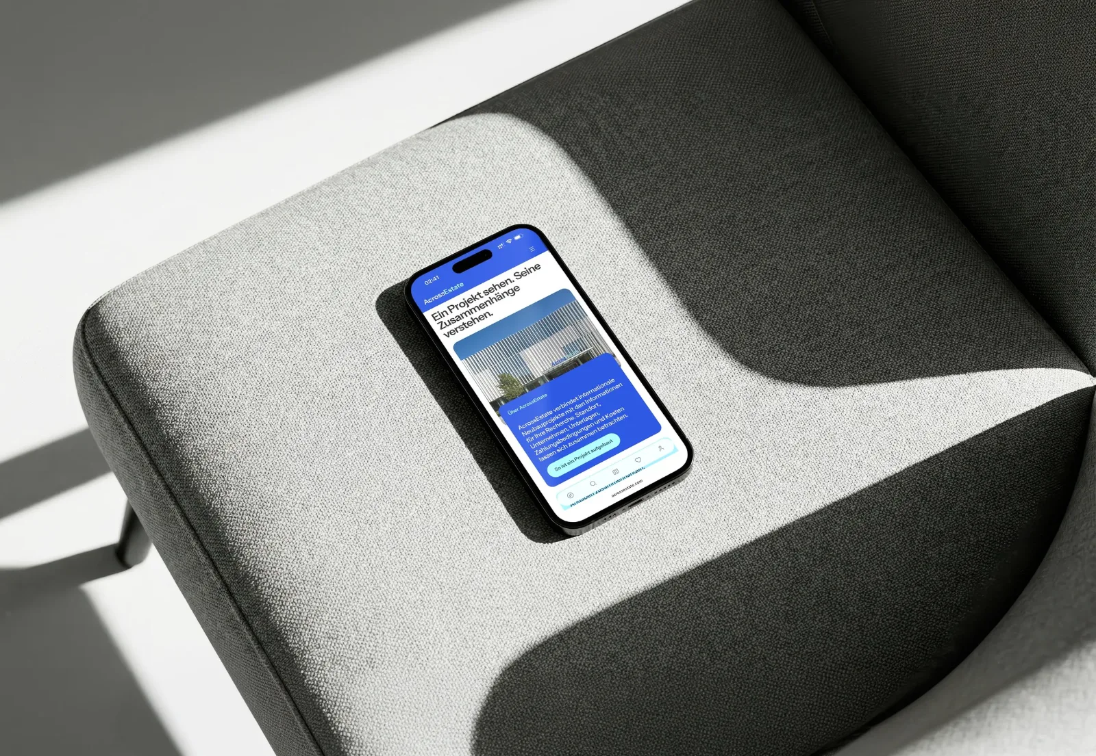 Across Estate auf einem Smartphone, das auf einem grauen Sessel liegt